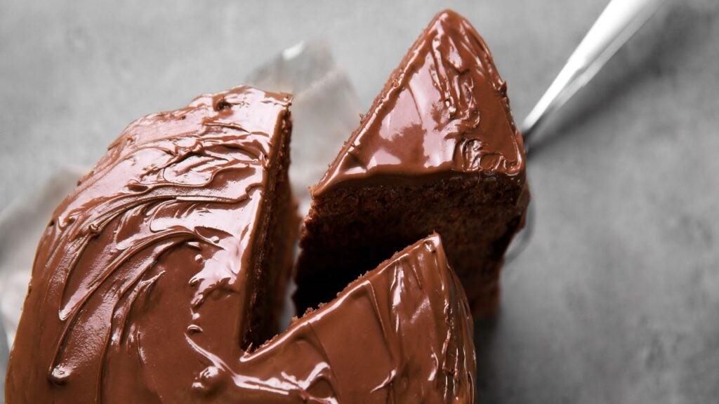 A piece of chocolate cake being removed from the whole